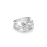 En sølvfarvet ring ligger på en hvid baggrund. Ringen har en organisk, skulpturel form, der ligner smeltet metal.