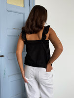 Modelfoto af pige som bærer en Amona top i sort, samt et par mørkeblå jeans. Alt fra By Sofie Sønderby