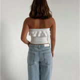 Modelfoto af pige der bærer en hvid stropløs Bonnie top, samt lyseblå Nanna jeans. Alt fra BySofieSønderby