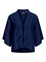 Mørkeblå kortærmet kimono med bindebånd foran. Påsyet mærke med teksten "JJXX" ved halsen. Baggrunden er hvid, hvilket fremhæver kimonoens farve og detalje.