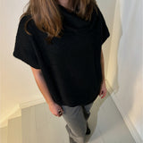 En person iført sort sweater står på en gråmalet trappe. Personen er delvist uden for billedet, med langt brunt hår og grå bukser. Væggen er hvid baggrund.