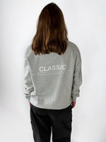Modelfoto af pige i grå CLASSIC sweatshirt med hvid tryk på ryggen. Modellen ses bagfra. Alt er fra BySofieSønderby