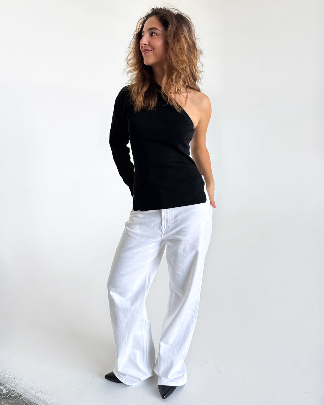 Modelfoto af pige i sort COLLINS one-shoulder, samt hvide NANNA jeans. Alt er fra BySofieSønderby