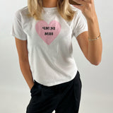 Kvinde tager selfie iført hvid t-shirt med lyserødt hjerte og teksten "DUMP HIM", mens hun står i et lyst rum.