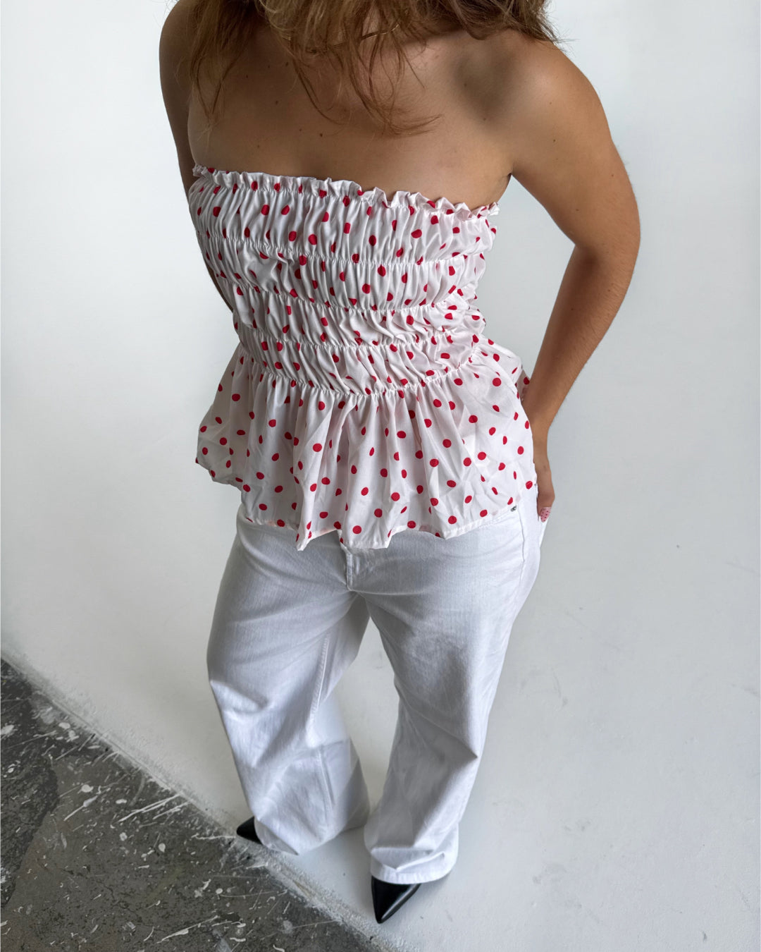 Modelfoto af pige i EMERIE top i hvid med røde prikker, samt hvide NANNA jeans. Alt er fra BySofieSønderby