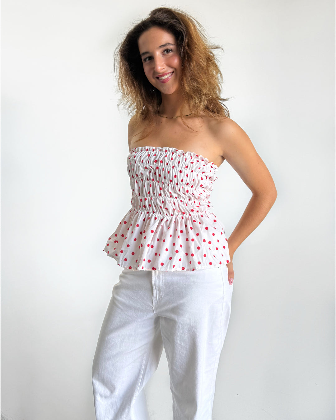 Modelfoto af pige i EMERIE top i hvid med røde prikker, samt hvide NANNA jeans. Alt er fra BySofieSønderby