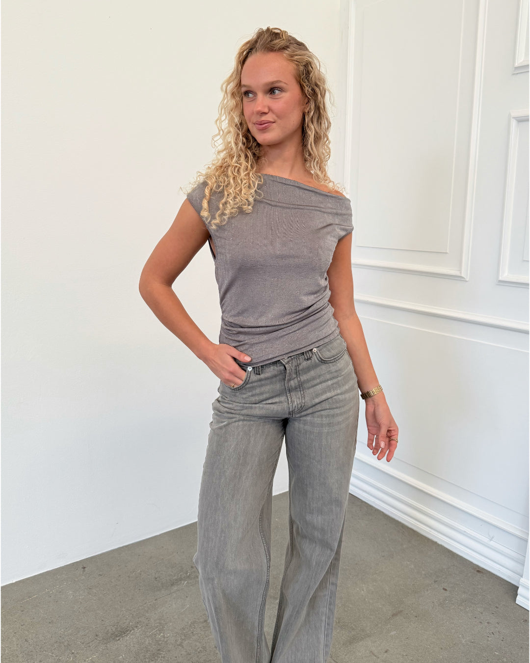 Modelfoto af pige i grå EVA glimmer top, samt grå NANNA JEANS. Alt er fra BySofieSønderby.