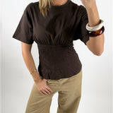 Stemningsbillede af pige der bærer en brun EVELYN smock t-shirt. Fra BySofieSønderby