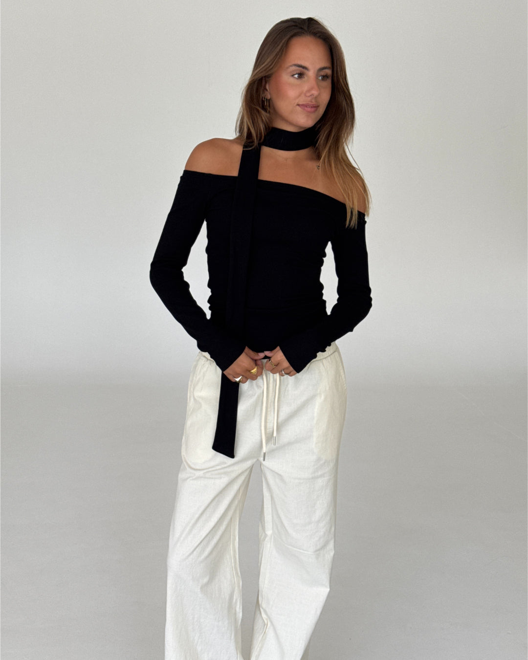 Modelbillede af FEO off shoulder bluse, sort og ELLEN bukser, creme. Begge fra BySofieSønderby