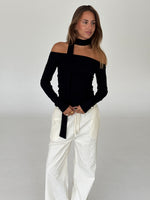 Modelbillede af FEO off shoulder bluse, sort og ELLEN bukser, creme. Begge fra BySofieSønderby
