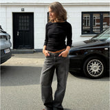 Modelfoto af pige i en sort Fifi boatneck bluse og grå Nanna jeans. Alt er fra BySofieSønderby