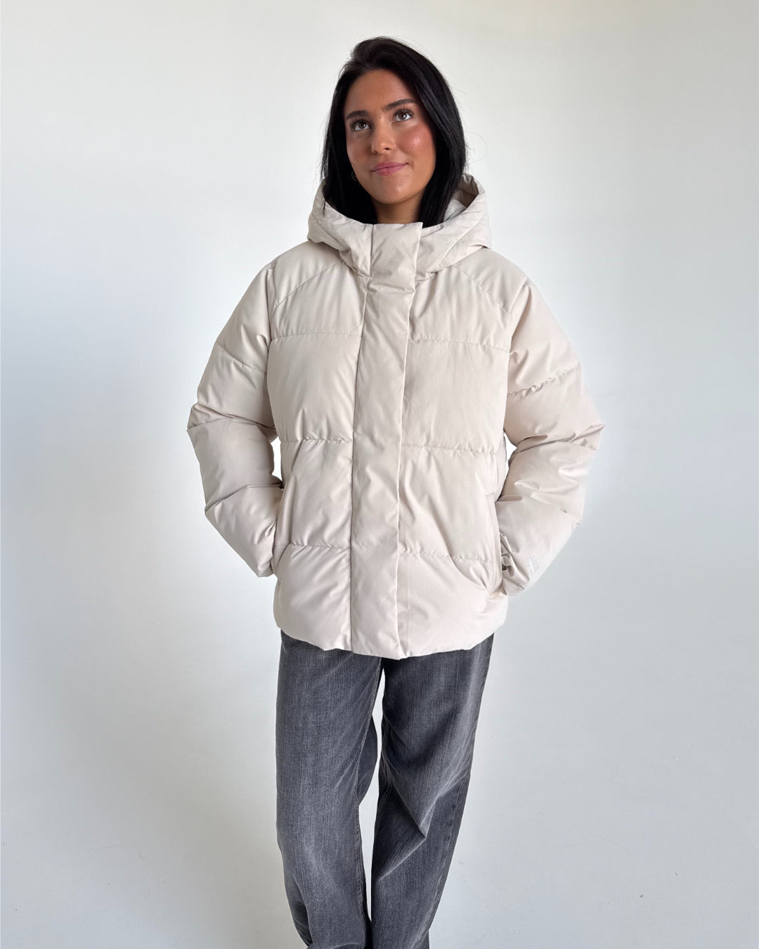 Modelfoto af pige i cremefarvet GLOBAL vinterjakke, samt grå NANNA jeans. Alt er fra BySofieSønderby