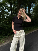 Modelfoto af pige i en sort Hadley polo og cremefarvede Adrianna jeans. Alt er fra BySofieSønderby