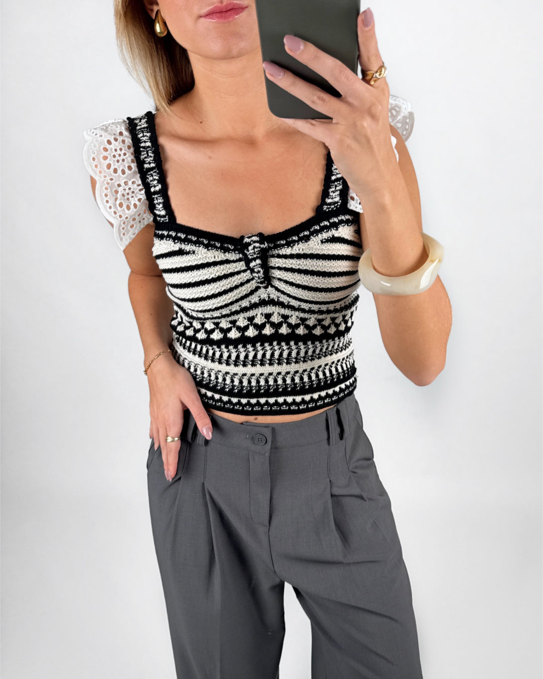 Modelfoto af pige i hvid KENDRA top med sorte detaljer, samt grå LISA bukser. Alt er fra BySofieSønderby.