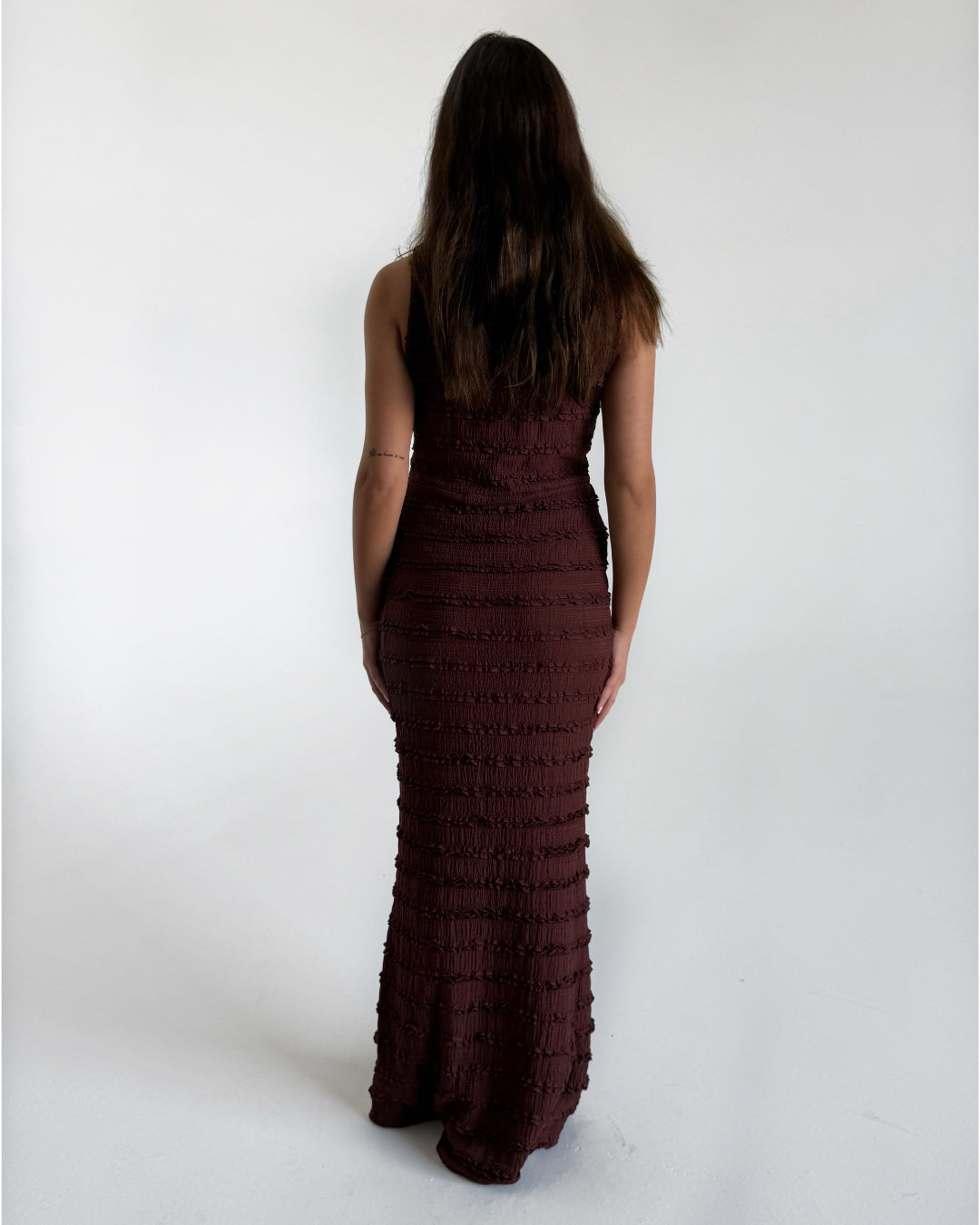 Modelfoto af pige i brun KIMBERLY kjole. Kjolen har tværgående detaljer. Pigen er set bagfra. Alt er fra BySofieSønderby