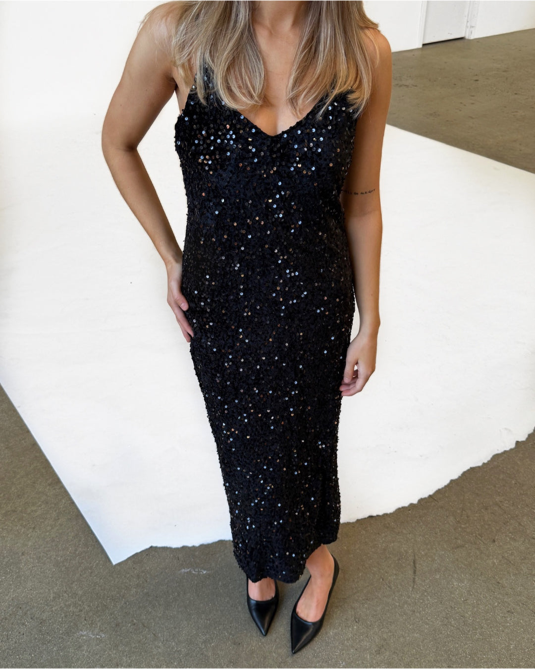 Modelfoto af pige i lang, sort KYLIE strop kjole med pailetter, samt sorte ballerinaer. Modellen ses forfra. Alt er fra BySofieSønderby