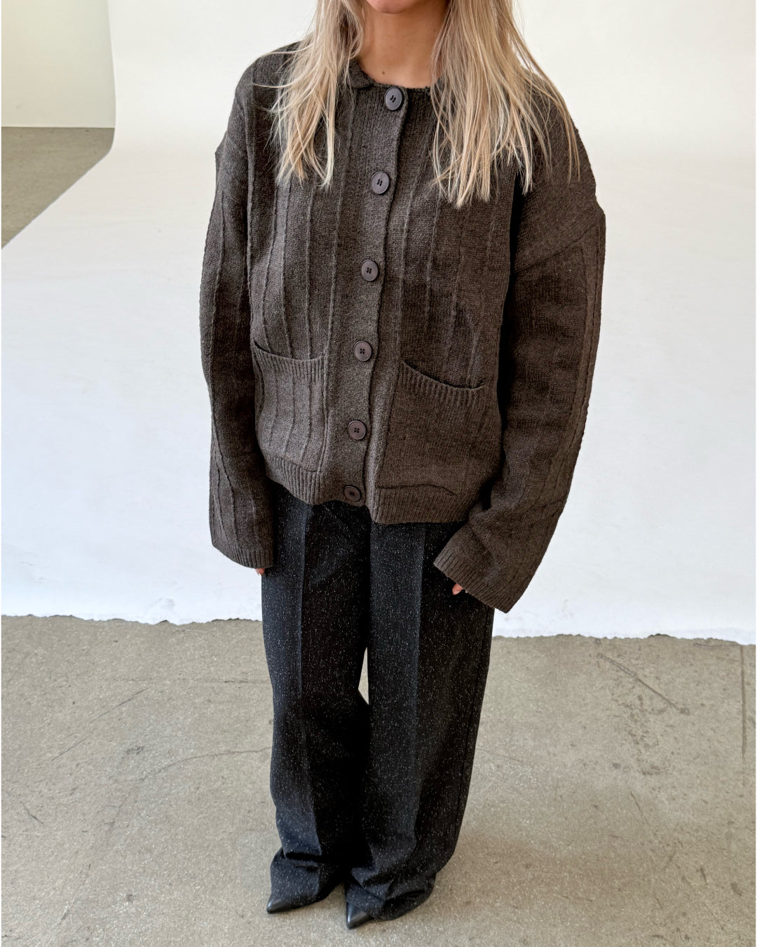 Modelfoto af pige i brun LACEY cardigan, samt sortmelerede ELLIS bukser. Alt er fra BySofieSønderby.