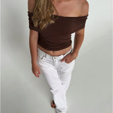 Modelfoto af pige som bærer en Leia top i brun, samt et par hvide Nanna jeans. Alt fra By Sofie Sønderby