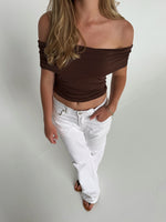 Modelfoto af pige som bærer en Leia top i brun, samt et par hvide Nanna jeans. Alt fra By Sofie Sønderby