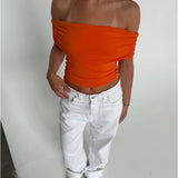 Modelfoto af pige som bærer en Leia top i orange, samt et par hvide Nanna jeans. Alt fra By Sofie Sønderby