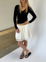 Modelbillede af LIZZY nederdel, creme og FREYA langærmet v-hals, sort. Fra BySofieSønderby