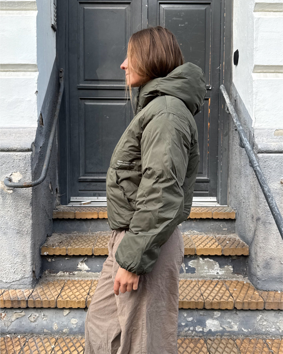 Modelfoto af pige i kakifarvet LOLLY vinterjakke, samt lysbrune cargopants. Alt er fra BySofieSønderby