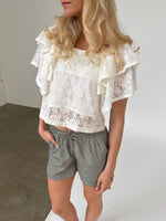 Modelfoto af pige iklædt LUCILLE blonde bluse, hvid og LANA shorts, grøn - begge fra BySofieSønderby