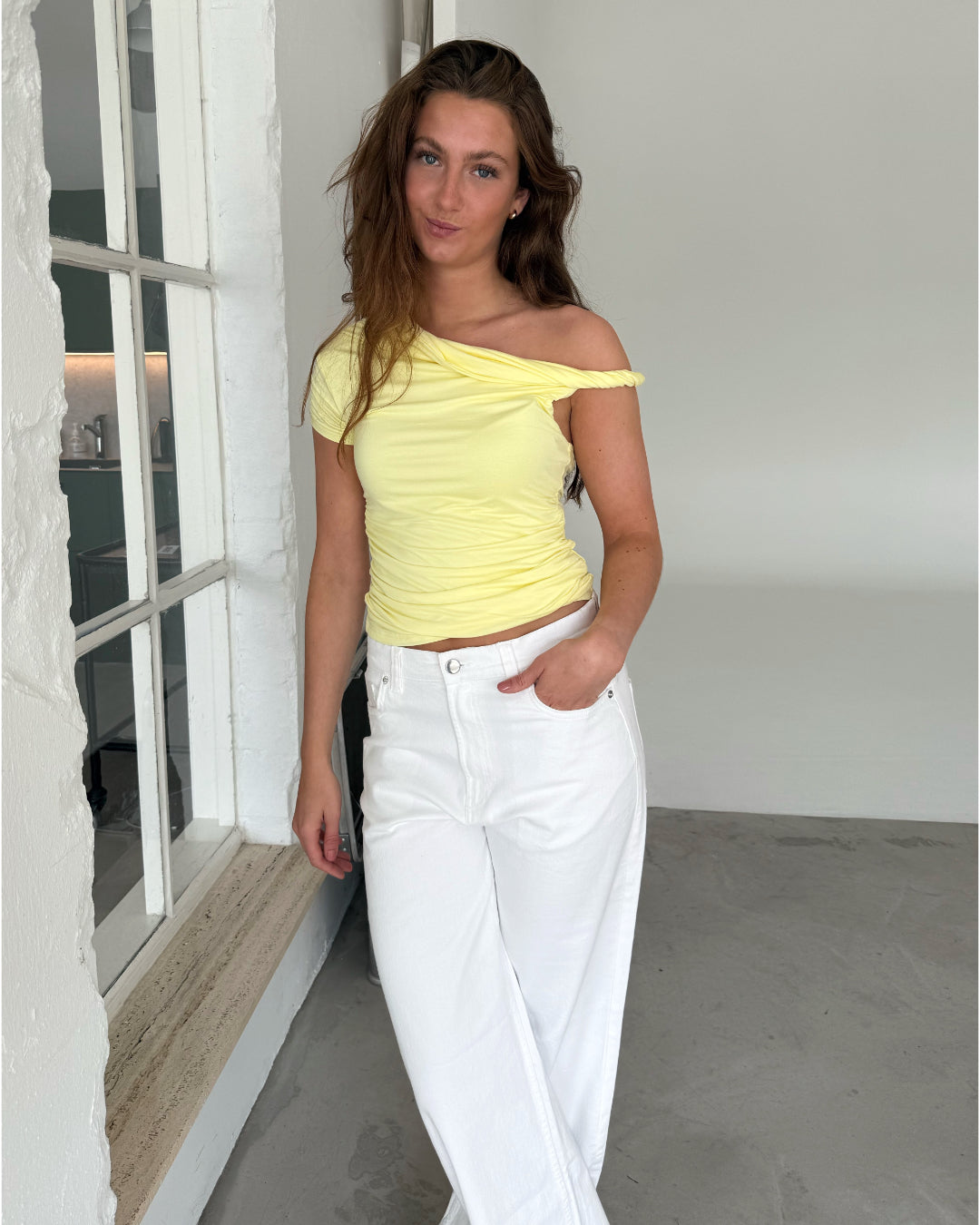 Modelfoto af pige med MILENA off shoulder top, gul og NANNA jeans, hvid - begge fra BySofieSønderby