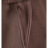 Brune joggebukser med elastisk linning og en lomme. Stoffet ser blødt og komfortabelt ud.