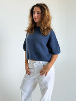 Modelfoto af pige i blå Poppy strik t-shirt og hvide Nanna jeans. Alt er fra BySofieSønderby