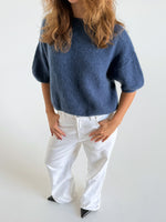 Modelfoto af pige i blå Poppy strik t-shirt og hvide Nanna jeans. Alt er fra BySofieSønderby