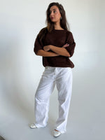 Modelfoto af pige i brun Poppy strik t-shirt og hvide Nanna jeans. Alt er fra BySofieSønderby