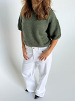 Modelfoto af pige i kaki Poppy strik t-shirt og hvide Nanna jeans. Alt er fra BySofieSønderby