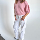 Modelfoto af pige i lyserød Poppy strik t-shirt og hvide Nanna jeans. Alt er fra BySofieSønderby