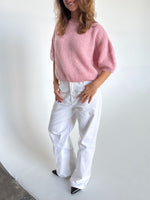 Modelfoto af pige i lyserød Poppy strik t-shirt og hvide Nanna jeans. Alt er fra BySofieSønderby