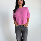 Modelfoto af pige i pink Poppy strik t-shirt og hvide Nanna jeans. Alt er fra BySofieSønderby