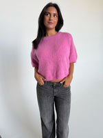 Modelfoto af pige i pink Poppy strik t-shirt og hvide Nanna jeans. Alt er fra BySofieSønderby