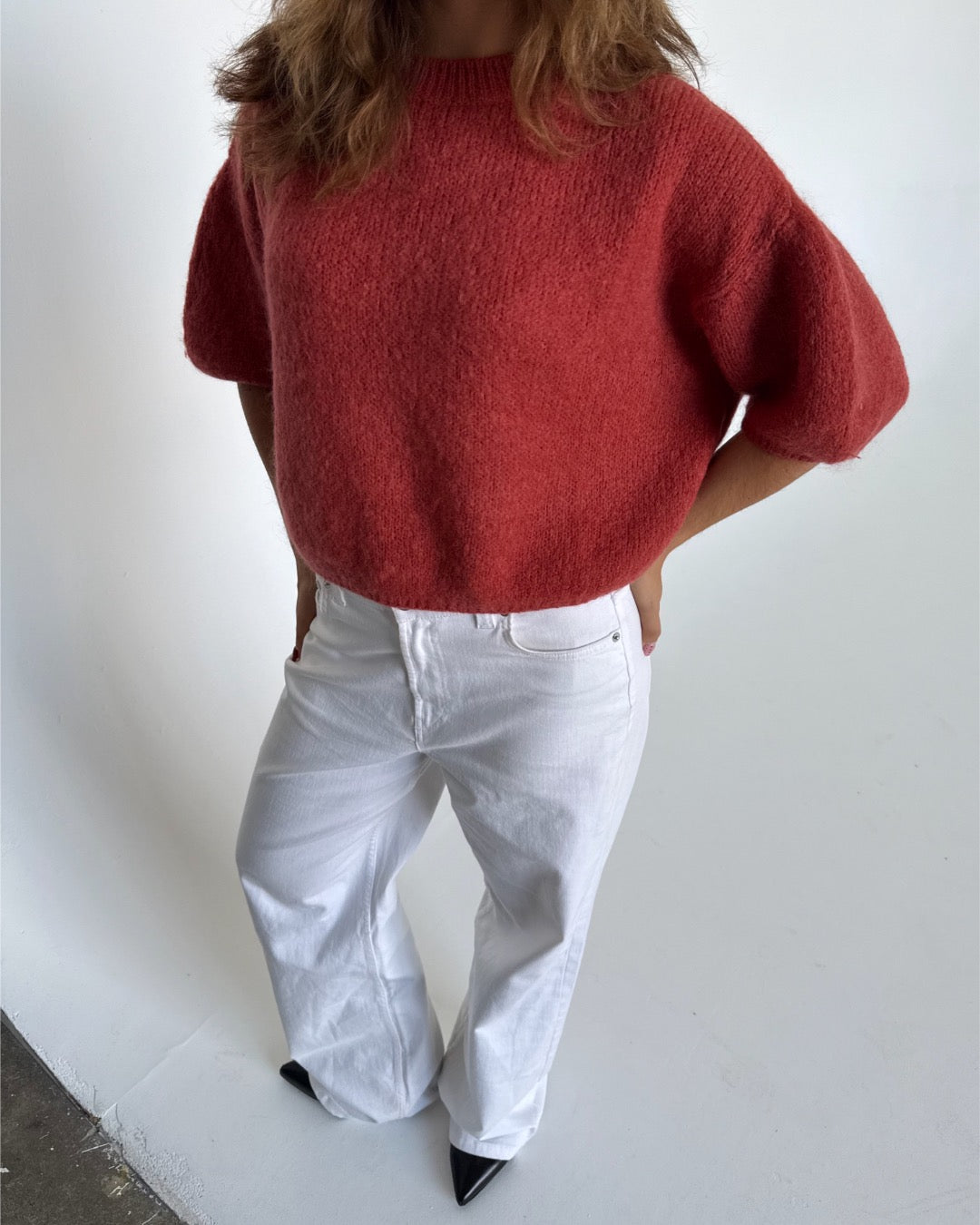 Modelfoto af pige i terracottafarvet Poppy strik t-shirt og hvide Nanna jeans. Alt er fra BySofieSønderby