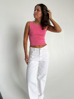 Modelfoto af pige som bærer en Posie top i pink, samt et par hvide Nanna jeans. Baggrund hvid. Alt fra By Sofie Sønderby