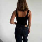 Modelfoto af pige som bærer en Posie top i sort, samt et par mørkeblå jeans. Alt fra By Sofie Sønderby