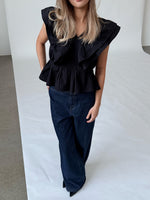 Modelfoto af pige i sort RIKKE top, samt mørkeblå TOKYO jeans. Alt er fra BySofieSønderby.