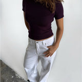 Modelfoto af pige i stramtsiddende kortærmet blommefarvet RIVKA t-shirt, samt hvide NANNA jeans. Alt er fra BySofieSønderby