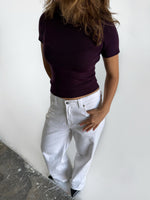 Modelfoto af pige i stramtsiddende kortærmet blommefarvet RIVKA t-shirt, samt hvide NANNA jeans. Alt er fra BySofieSønderby