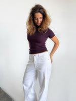 Modelfoto af pige i stramtsiddende kortærmet blommefarvet RIVKA t-shirt, samt hvide NANNA jeans. Alt er fra BySofieSønderby