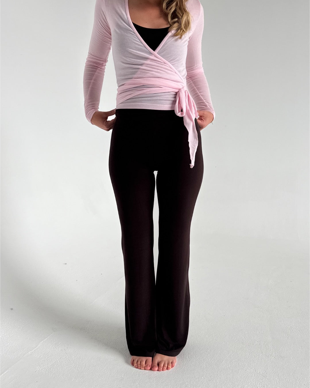 Modelfoto af pige i brune Sania yoga bukser og lyserød Luna wrap bluse. Fra BySofieSønderby