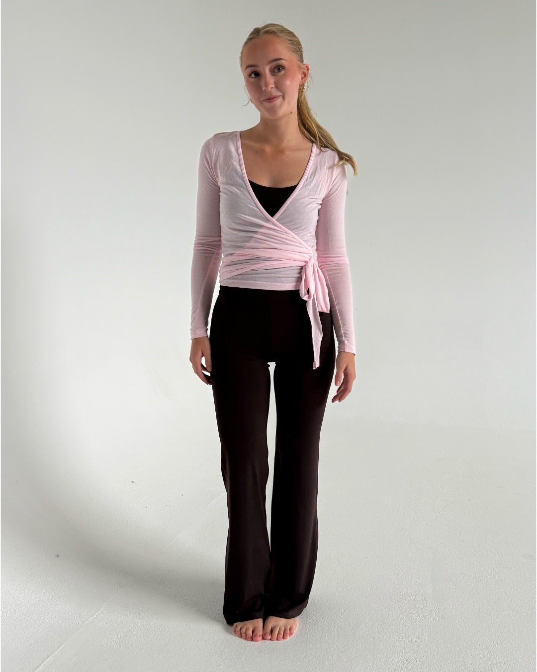 Modelfoto af pige i brune Sania yoga bukser og lyserød Luna wrap bluse. Fra BySofieSønderby