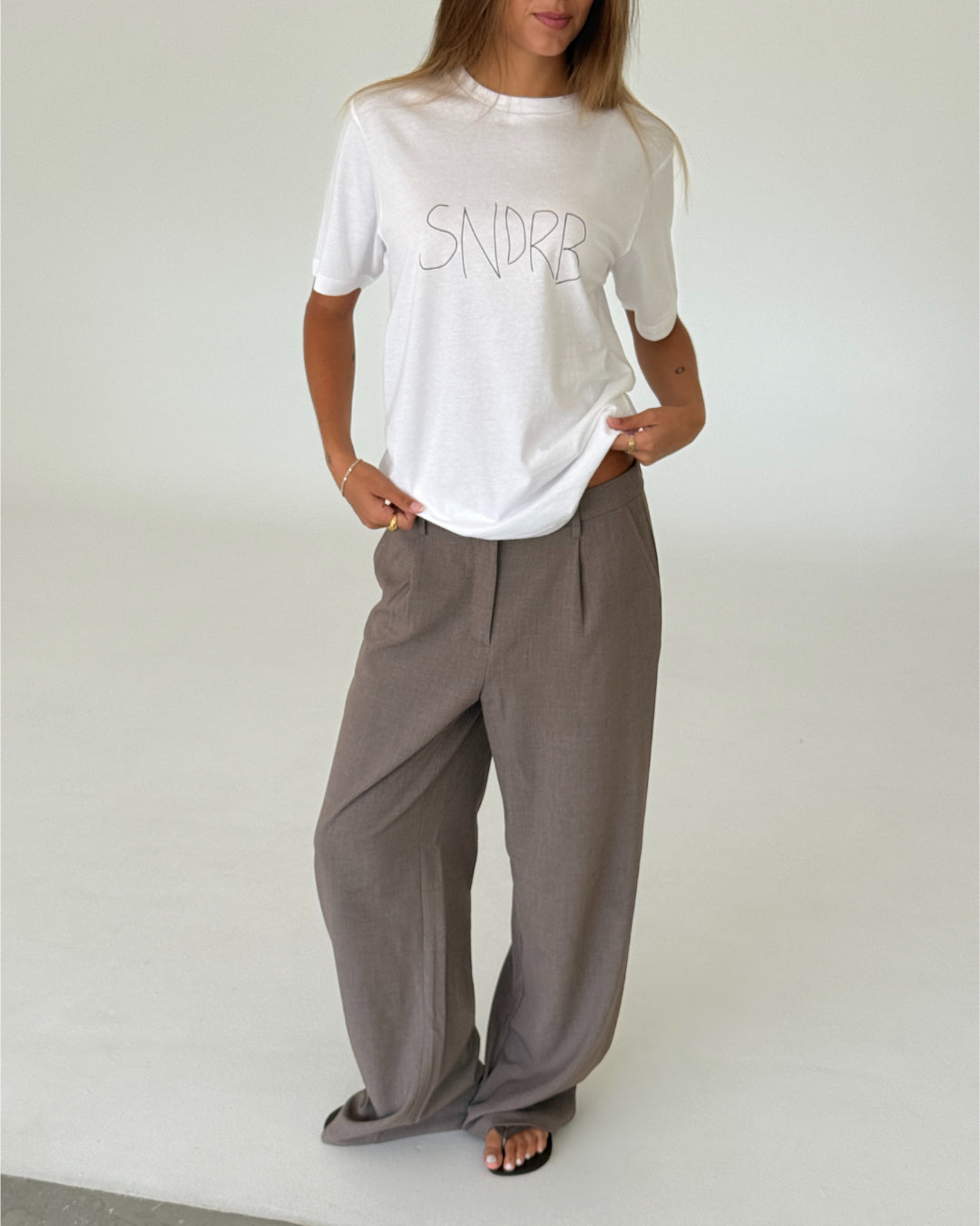 Modelbillede af SNDRB DRAW t-shirt, hvid/sort og KARI bukser, sand. Begge fra BySofieSønderby