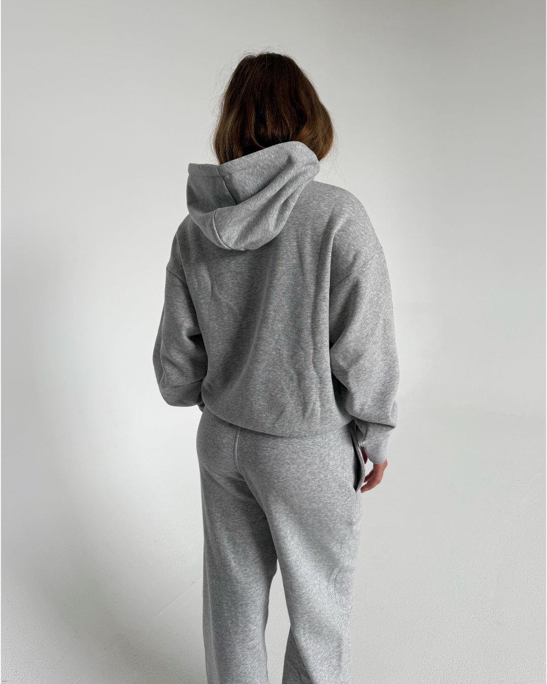 Modelfoto af pige som bærer en Studio Vesterbro hoodie i grå, samt Studio Vesterbro bukser i grå. Alt fra By Sofie Sønderby