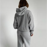 Modelfoto af pige som bærer en Studio Vesterbro hoodie i grå, samt Studio Vesterbro bukser i grå. Alt fra By Sofie Sønderby