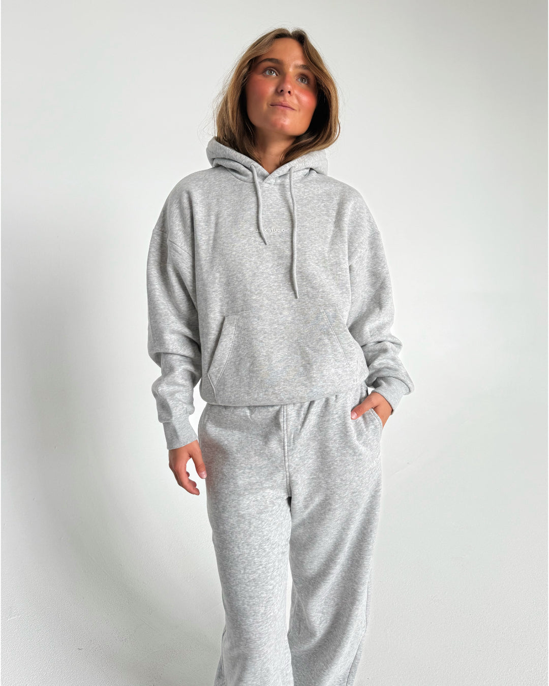 Modelfoto af pige som bærer en Studio Vesterbro hoodie i grå, samt Studio Vesterbro bukser i grå. Alt fra By Sofie Sønderby